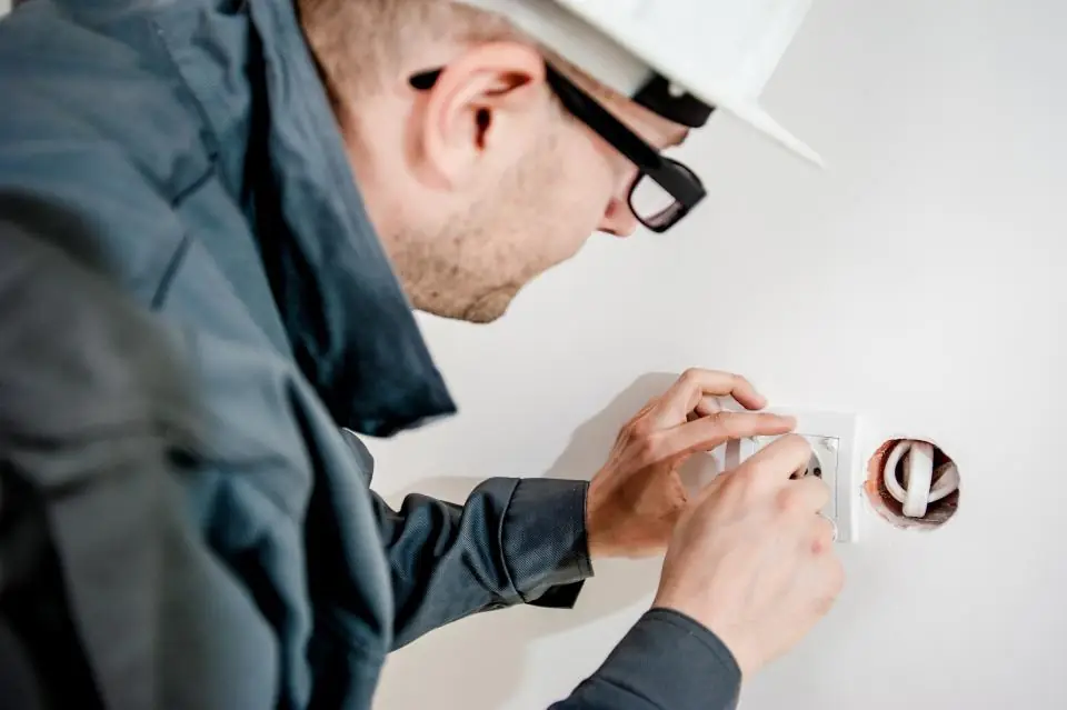 Electrician in a hard hat and work jacket fitting a socket